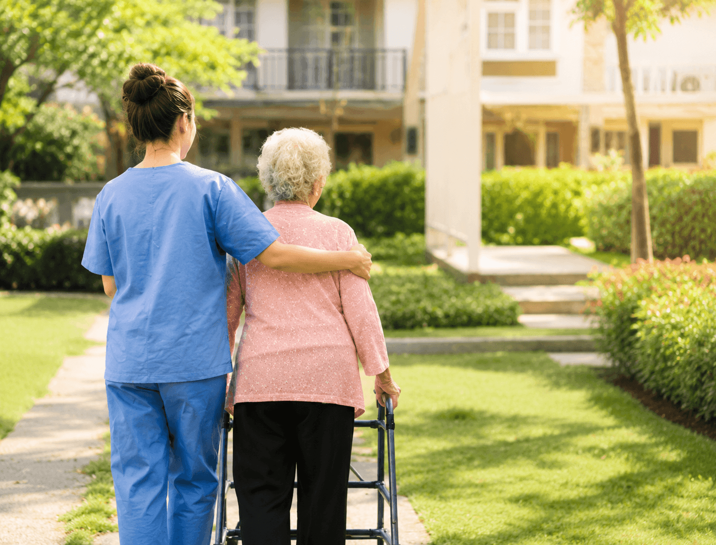 Pflegekraft begleitet Seniorin mit Rollator im Freien